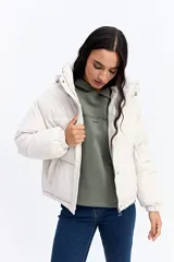 Campera puffer color crema con capucha, cuello alto, cierre frontal y puños elásticos.