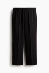 Pantalón de corte relajado con cintura elástica y cordón de ajuste. Presenta pliegues frontales y traseros, bolsillos laterales discretos y un bolsillo trasero insertado.
