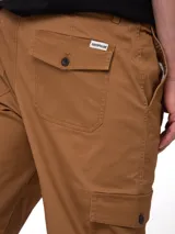 Pantalon cargo de corte ajustado en color marrón, con bolsillos laterales tipo cargo con solapa y bolsillos traseros abotonados. Cuenta con cierre de cremallera y botón, además de elástico interior en la cintura para mayor comodidad.