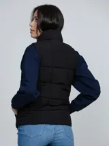 Chaleco acolchado Tommy Hilfiger de color negro, con cuello alto, cierre frontal de cremallera y dos bolsillos laterales de ojal.