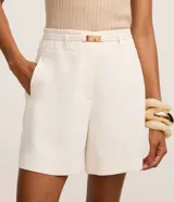 Short sastre de corte recto color blanco, con cintura alta, trabillas y cinturón integrado con hebilla metálica.