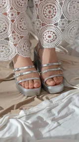 Sandalias plateadas con plataforma y tacón ancho, tiras finas con hebillas y pulsera al tobillo.