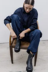 Bota corta de cuero negro con cierre frontal con cremallera y suela de goma.