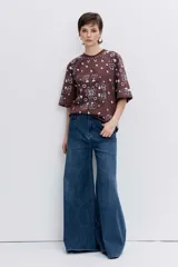 Remera de corte oversize color marrón con estampado tipo bandana en color blanco. Presenta cuello redondo y mangas cortas amplias.