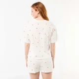 Conjunto de pijama de dos piezas confeccionado en punto de algodón blanco con estampado de pequeños corazones rojos, compuesto por una camiseta de manga corta y cuello redondo de corte holgado, y un pantalón corto con cintura elástica.