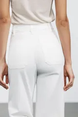 Pantalón de jean blanco de tiro alto y corte wide leg, con bolsillos delanteros y traseros. Cierre frontal con cremallera y botón metálico.