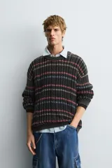 Jersey de punto con ajuste relajado, cuello redondo y manga larga. Presenta un diseño de rayas horizontales multicolores sobre una base oscura con textura de ochos y efecto lavado.