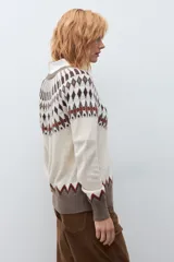 Cardigan de punto con diseño jacquard en tonos beige, marrón y rojo. Presenta cuello redondo, cierre frontal con botones y puños acanalados.