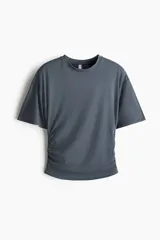 Remera gris oscuro de punto suave, con hombros caídos, mangas cortas y frunces laterales.