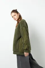 Buzo negro de tela tipo teddy, de manga larga y cuello redondo. Presenta recortes de nylon en mangas y laterales.