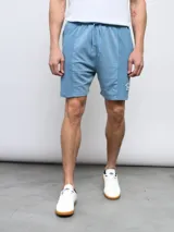 Bermuda de felpa negra con efecto lavado, corte recto y cordón ajustable en la cintura. Presenta un panel vertical en la parte delantera de cada pierna y el logo Umbro bordado en blanco en el muslo izquierdo.