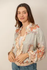 Campera ligera con cierre frontal, cuello mao y estampa de motivos florales y ornamentales en tonos celestes y naranjas.