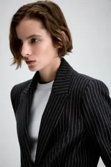 Blazer entallado con diseño peplum, confeccionado en tela con estampado de raya diplomática. Presenta cuello con solapas de muesca, cierre frontal con un botón, mangas largas y bolsillos delanteros con solapa.