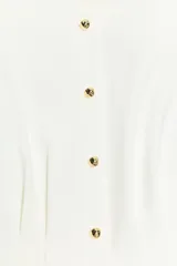 Chaleco entallado blanco con cuello redondo, manga sisa, pinzas estructuradas, detalle de peplum en la parte inferior y cierre frontal con botones dorados.