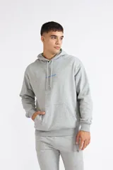 Canguro Quiksilver modelo Fractured Wave de color gris melange, con capucha ajustable mediante cordón, bolsillo tipo canguro frontal y pequeño estampado azul en el pecho.