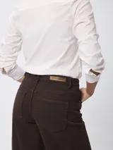 Jean de corte wide leg en color marrón, con tiro medio, cierre de botón y cremallera, y diseño clásico de cinco bolsillos.