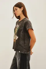Remera de algodón con efecto lavado, cuello redondo y mangas cortas. Presenta un estampado frontal con un guepardo rodeado de flores y la palabra 'SAVAGE' en letras doradas.