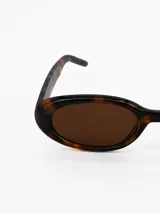 Lentes de sol con armazón ovalado de carey y cristales oscuros.