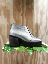 Botinetas plateadas de cuero vacuno con punta cuadrada, cierre trasero y taco de madera con plataforma.