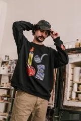 Buzo negro de corte holgado con cuello redondo y puños y cintura acanalados. Estampado frontal con imágenes de un encendedor, una pipa, una caja de cigarrillos y un cenicero.