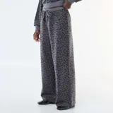 Pantalón de corte ancho con estampado de leopardo en tonos grises, confeccionado en tejido suave, con cintura elástica y cordón ajustable.