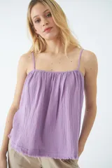 Blusa de tirantes finos ajustables, con diseño holgado y ruedo desflecado. Confeccionada en tela de textura arrugada.