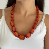 Collar de cuentas tubulares de resina brillante con efecto degradé en tonos rojizos y anaranjados, con cierre de rosca.