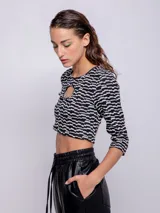 Top corto negro con estampado de líneas onduladas blancas, mangas 3/4 y abertura circular en el pecho.