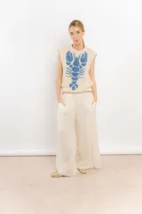 Chaleco tejido a mano en lana merino, color beige con diseño de langosta en color azul y detalles de terminación en rojo en cuello y sisas.