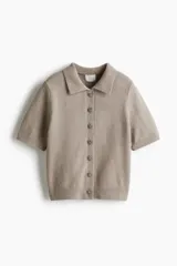 Saco de manga corta en punto suave color beige, con cuello camisero, cierre frontal de botones con strass y terminaciones acanaladas en mangas y bajo.