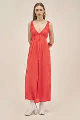 Vestido largo color coral, sin mangas, confeccionado en crepe. Presenta breteles finos que se atan para regular el largo y dos tiras en el pecho que se pueden atar de diferentes maneras.