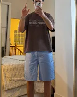 Remera marrón oversize de manga corta con estampado gráfico en la espalda de dos gatos de estilo retro con cuchillos y texto "Kahoa Industries".