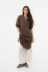 Vestido camisero midi de lino color beige, de calce relajado, con cuello clásico, cierre frontal parcial con botones, mangas 3/4 regulables y bolsillos delanteros.