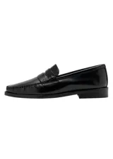 Zapato tipo mocasín de cuero vacuno color negro, con diseño de punta redonda, costuras visibles y detalle de antifaz en el empeine.