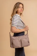 Bandolera de tafeta impermeable color beige, con dos bolsillos frontales con cierre y correa regulable. Diseño práctico y liviano ideal para uso diario.