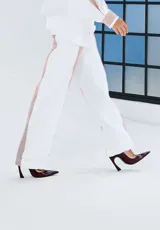 Pantalón blanco de corte recto con franjas laterales a rayas rojas, bolsillos laterales y cintura elastizada.