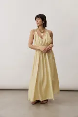 Vestido largo color amarillo con tirantes finos cruzados en la espalda, escote en V y diseño fluido con falda amplia.