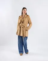 Campera tipo trench de color habano, de corte a la cadera, confeccionada en material textil símil gamuza. Presenta solapa cruzada, doble botonadura frontal, hombreras y cinturón ajustable para anudar en la cintura. Incluye bolsillos delanteros y puños con trabilla.