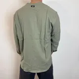 Camisa de lino color verde militar, de manga larga con puños doblados, cuello mao y cierre frontal con botones.