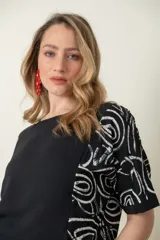 Blusa negra de mangas cortas con estampado abstracto en blanco y corte holgado. 