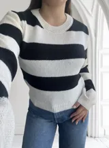 Sweater de punto a rayas horizontales anchas en blanco y negro, con cuello redondo y mangas largas.