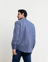 Camisa celeste con microestampado blanco, de corte clásico, manga larga y cuello abotonado. Tiene un bolsillo en el pecho.
