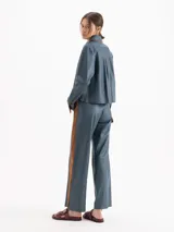 Pantalon sastrero recto confeccionado en cuero ovino color azul, con franjas laterales en color tostado y detalle de botones a lo largo de la pierna.