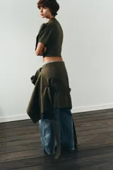 Jersey de punto de manga corta y cuello redondo, en color verde oliva. Presenta un detalle de lazo grande en el frente que le otorga un toque distintivo y femenino.