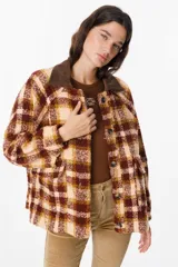 Chaqueta de corte holgado con estampado de cuadros en tonos beige, marrón y amarillo. Presenta cuello camisero en pana marrón, cierre frontal con botones y mangas largas con puños abotonados.