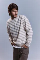 Buzo de cuello redondo con diseño de rayas horizontales en tonos crudo y beige, de corte holgado y mangas largas con puños elásticos.