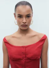 Vestido midi de corte evasé confeccionado en mezcla de lino y lyocell. Presenta escote barco, tirantes anchos y cierre frontal con botones a tono. Incluye detalle de lazo en la parte posterior.