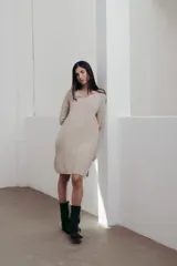 Vestido midi de tejido de punto fino en color beige, con escote en V y diseño de corte holgado. Presenta una textura acanalada y mangas largas.