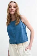 Top de denim sin mangas, con cuello redondo y costuras pespunteadas en el frente, confeccionado en tela de mezclilla azul.