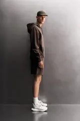 Sudadera de hombre Zara Athleticz de ajuste relajado (relaxed fit), color marrón, confeccionada en tejido técnico compacto con mezcla de algodón y elasticidad. Cuenta con cuello con capucha ajustable con cordones negros, manga larga, bolsillo frontal tipo canguro con un pequeño bolsillo termofijado con cierre, y acabados con rib en puños y cintura.